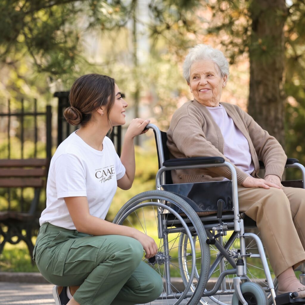 CAAE Health caregiver with an older woman in a wheelchair outdoors